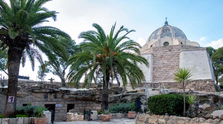 A wide angle image of the entrance to the Chapel of the Shepherds’ Field with palm trees in the Holy Land