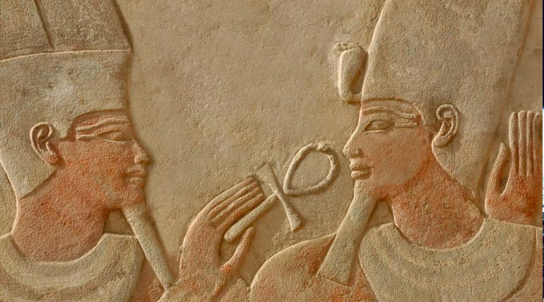 Wall engraving of two ancient Egyptians facing each other and holding The Ankh Cross